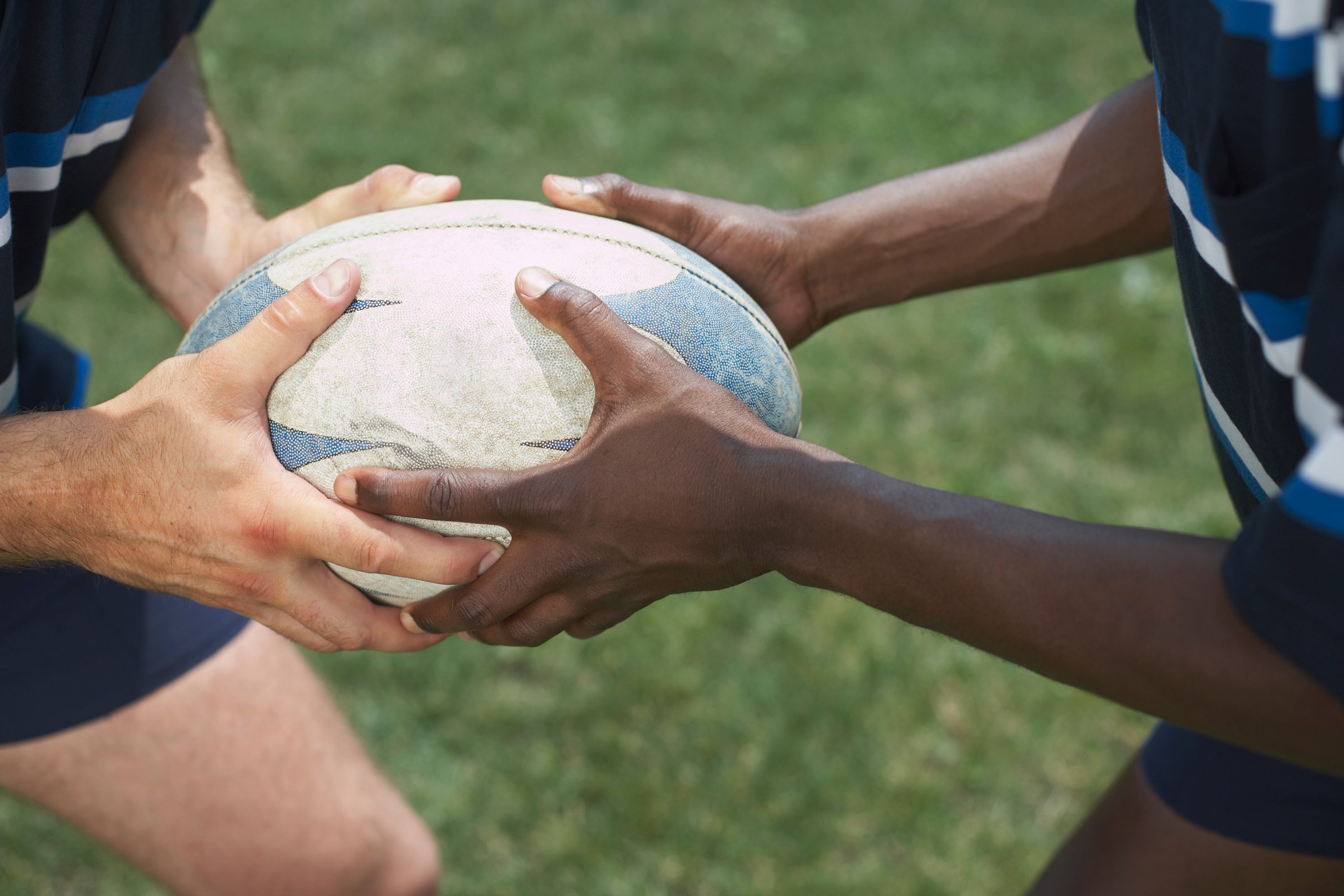 Hands holding rugby ball